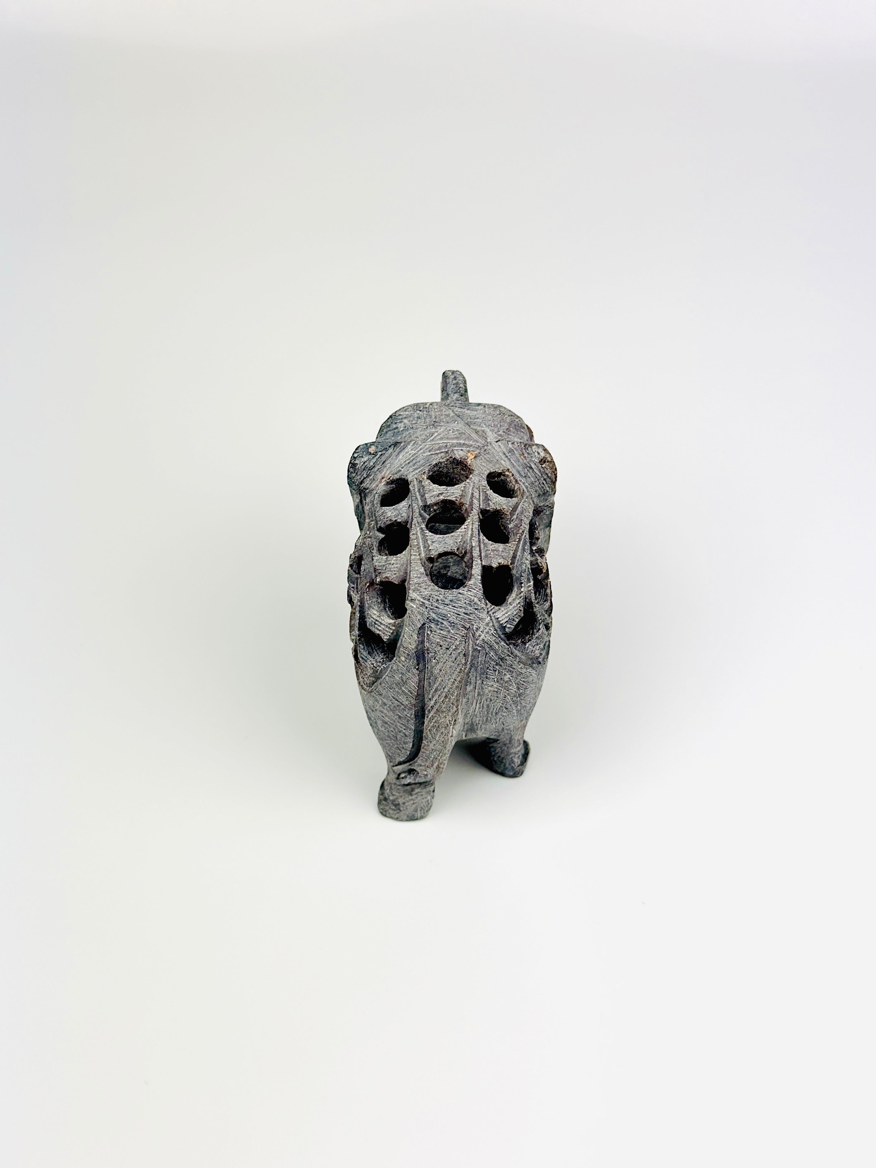 Back view of Cairo stone elephant with intricate carvings on white background
